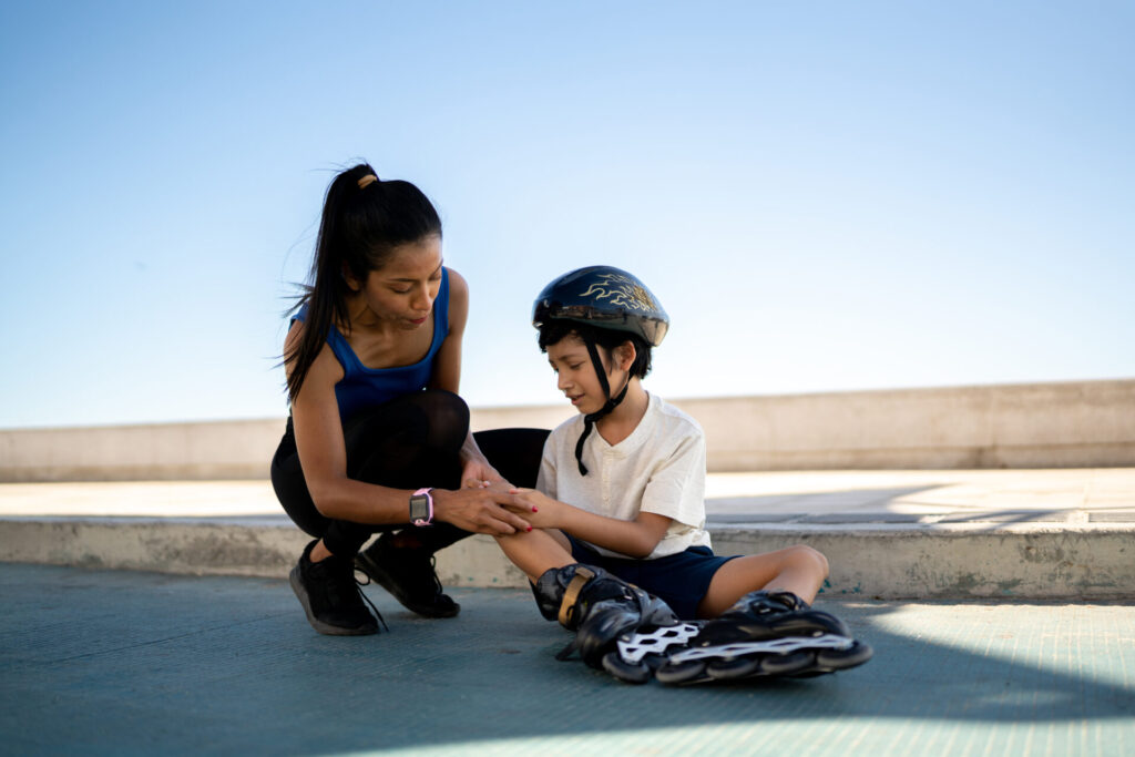 mom comforting son in rollerblades, clutching his leg