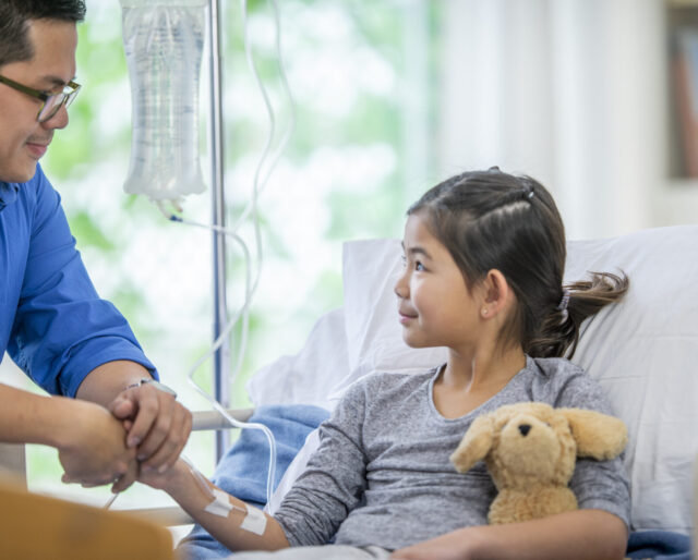 girl with IV being comforted by dad