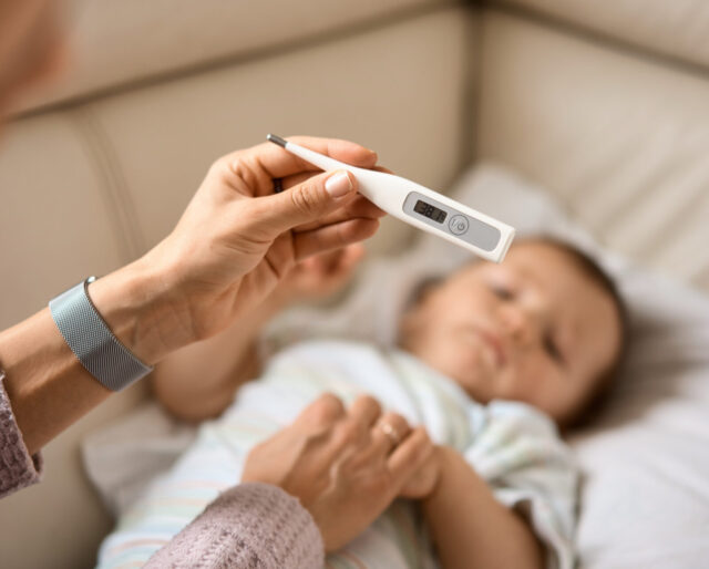 parent measuring child's temperature