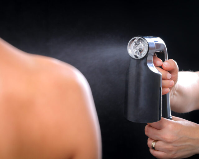 a spray tan being applied to a shoulder