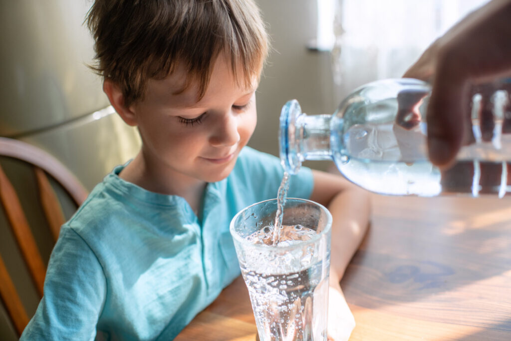 young boy drinking water out of a glass