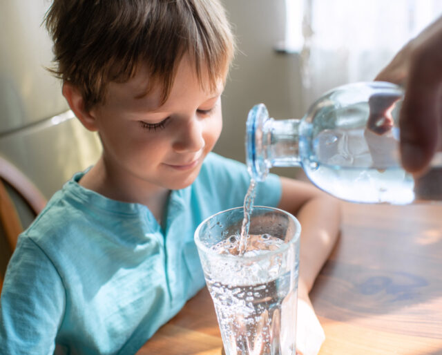 young boy drinking water out of a glass