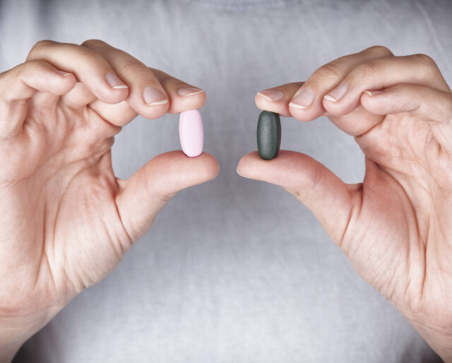 Woman holding colored pills in her hands. Close up.