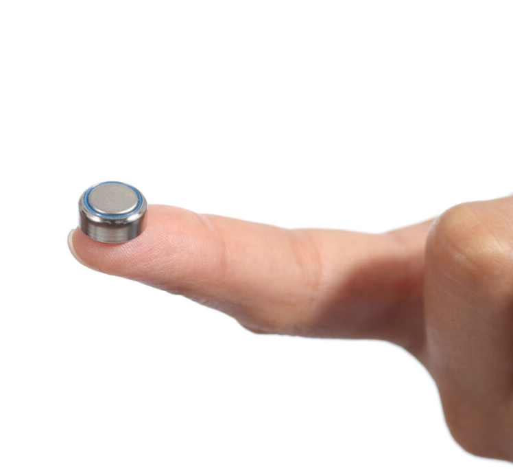 Woman hand holding a button battery with the forefinger isolated on a white background