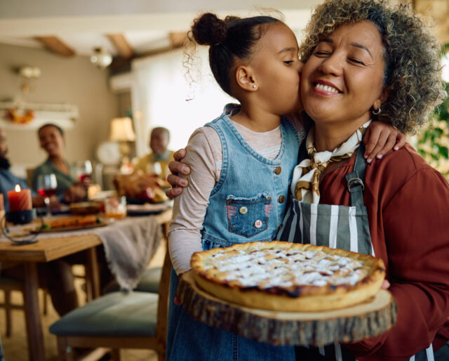 Affectionate grandmother and granddaughter with freshly baked holiday pie.