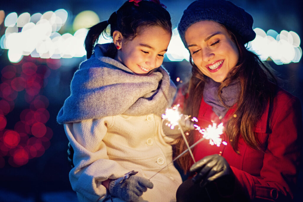 woman and child smiling at sparklers at New Years