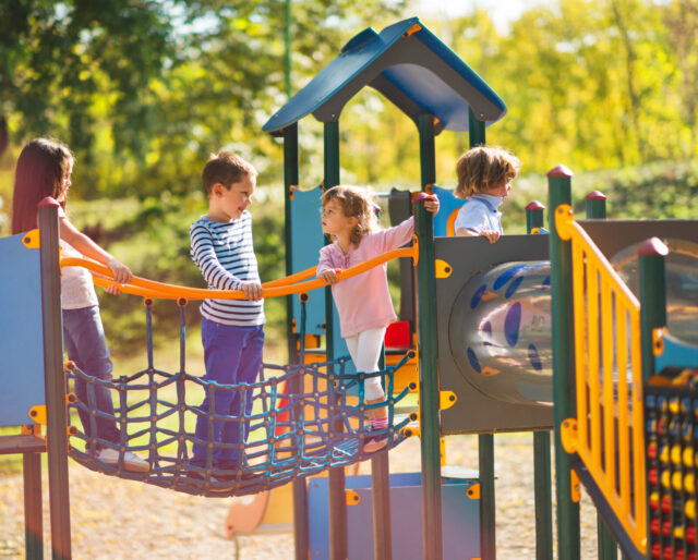 Children playing on a playground, boy and girl facing each other and talking