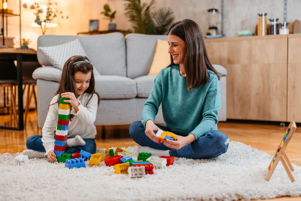 Mom and daughter sitting on the floor, playing with blocks