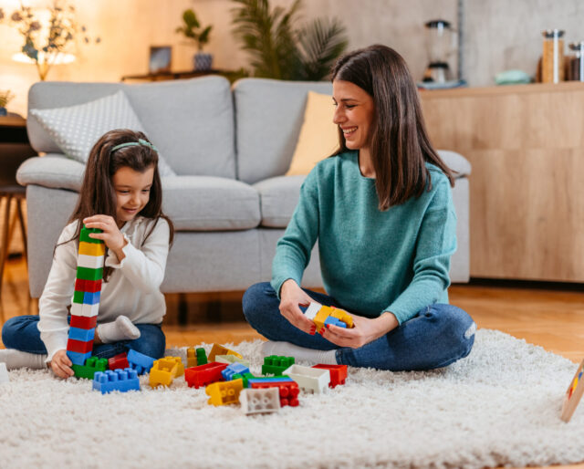 Mom and daughter sitting on the floor, playing with blocks