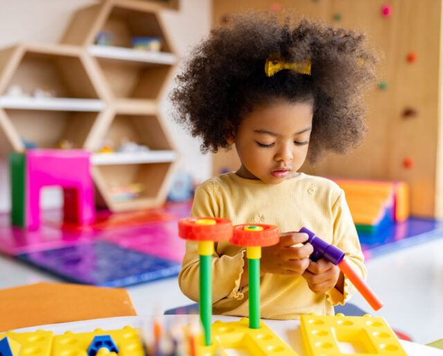 young girl playing by herself with a colorful construction set