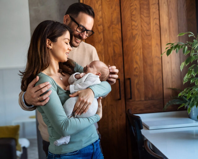 smiling father and mother embracing new born child.