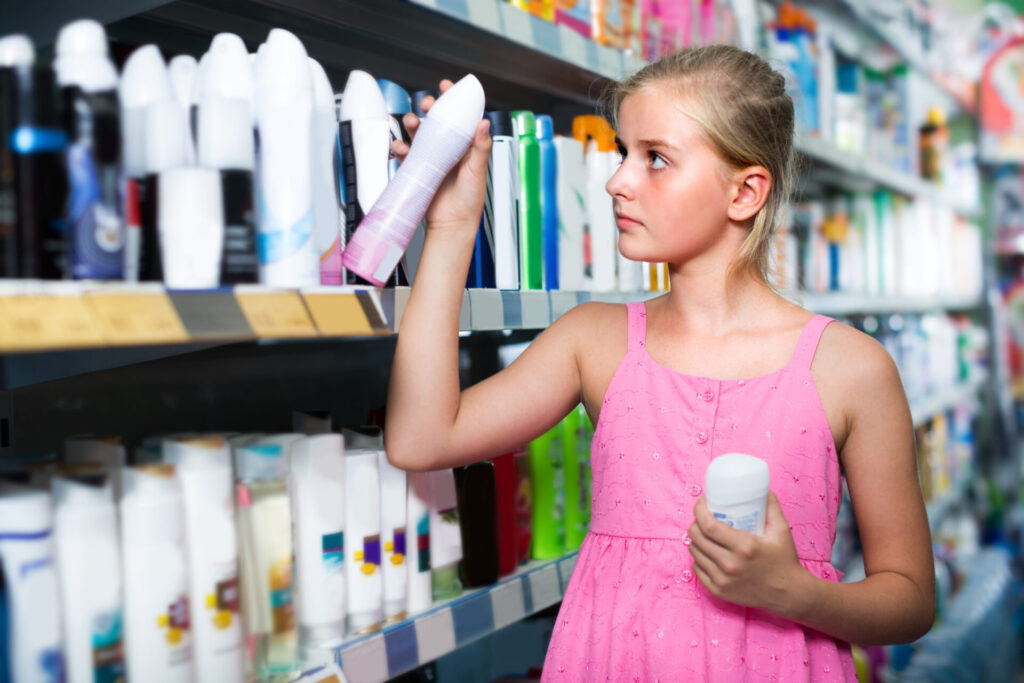 Customer girl is choosing deodorant in the supermarket.