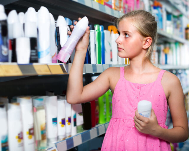 Customer girl is choosing deodorant in the supermarket.