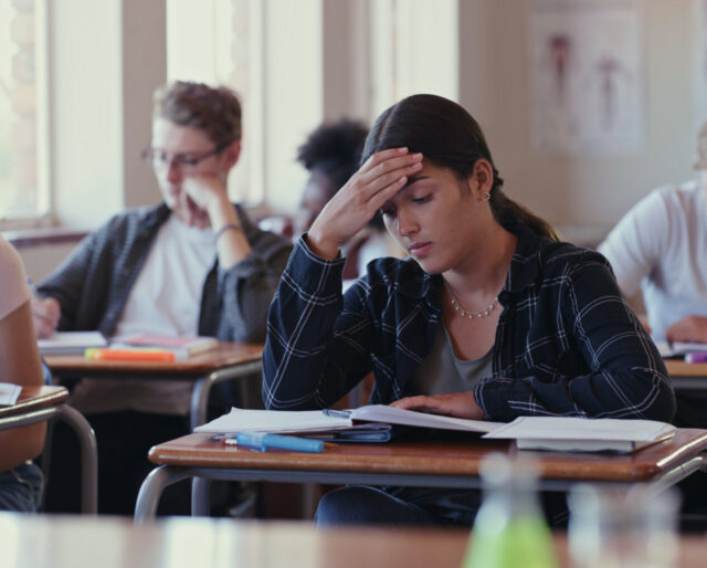 Shot of a student struggling with schoolwork in a classroom