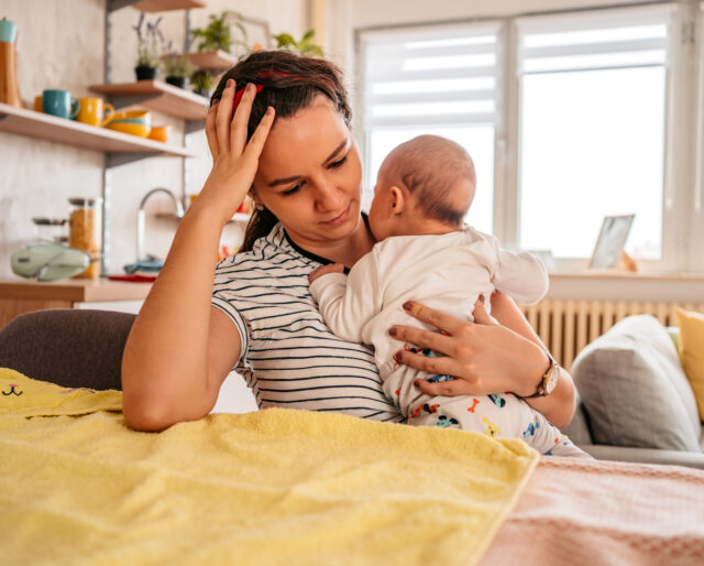 Mother holding her newborn baby feeling sleepy